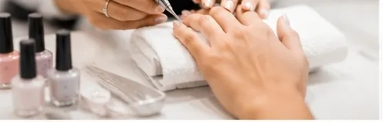 A close-up of a manicure in progress beside a row of nail polish bottles